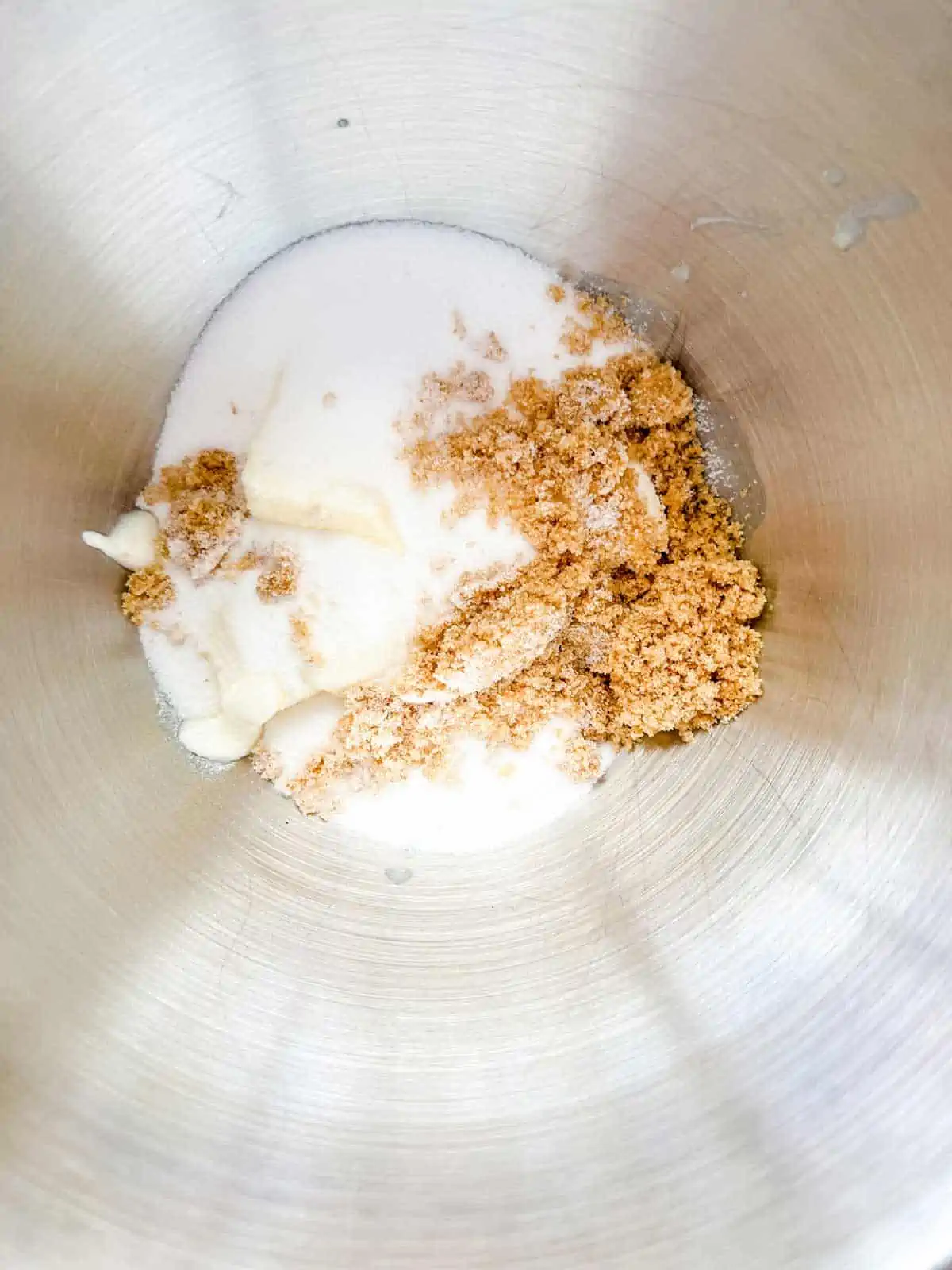 Photo of white sugar, brown sugar, and butter in the bowl of a stand mixer.