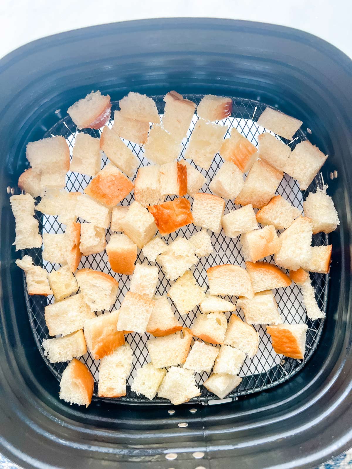 Bread cubes in an air fryer.