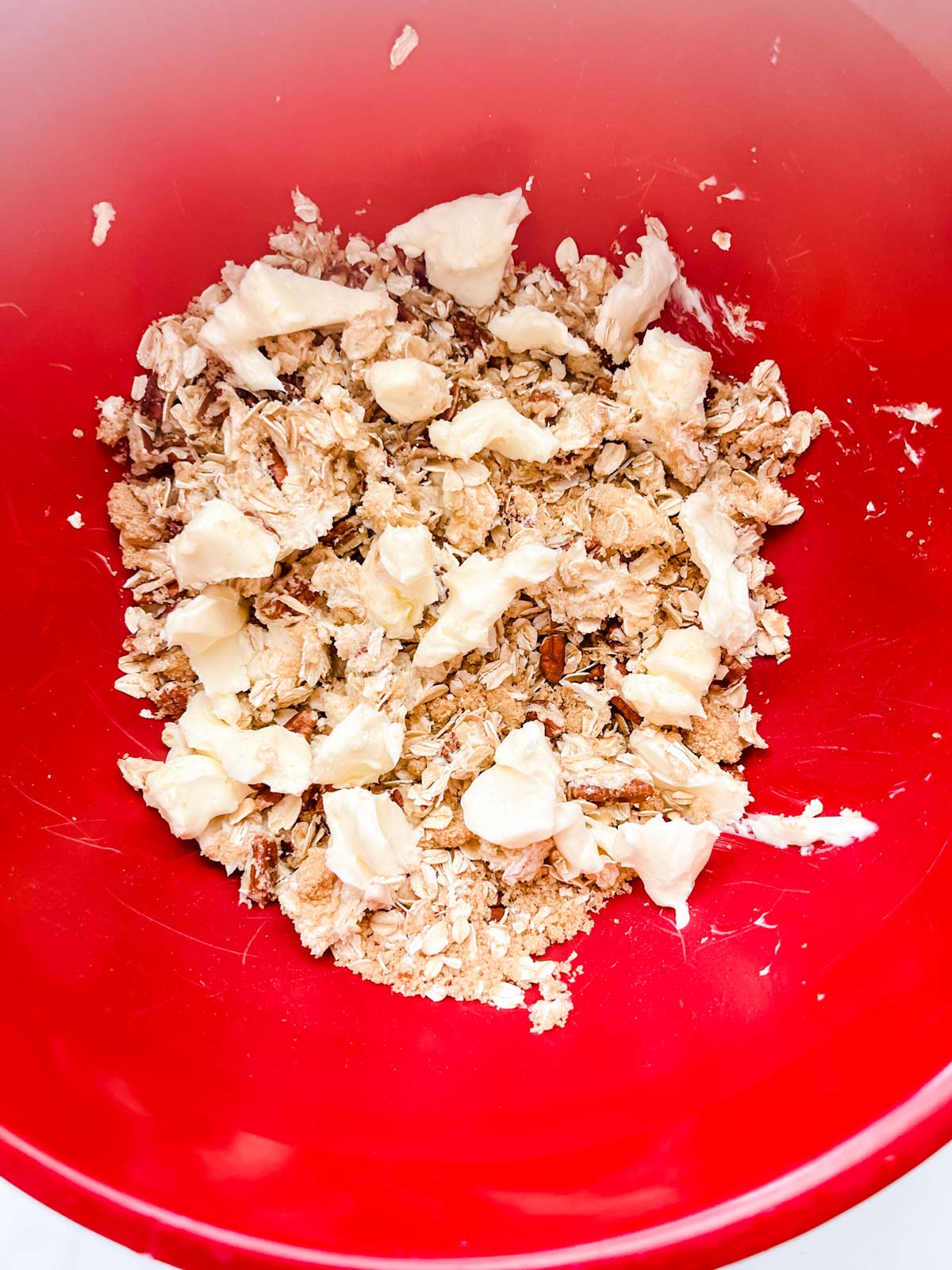 Cubed butter on top of brown sugar, oats and pecans in a red bow.