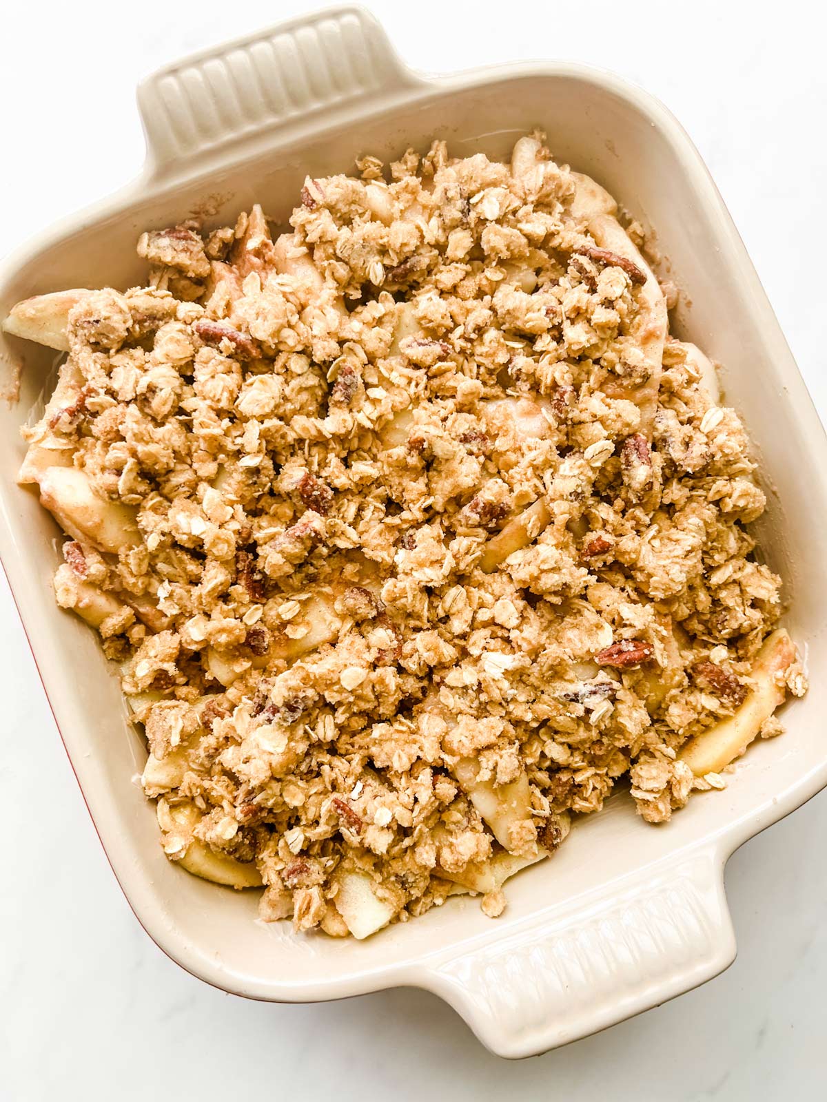 Crisp topping on top of apples and pears in a square casserole dish.
