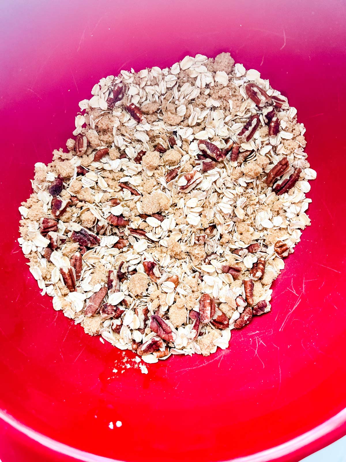 Oats, brown sugar, and pecans in a red bowl