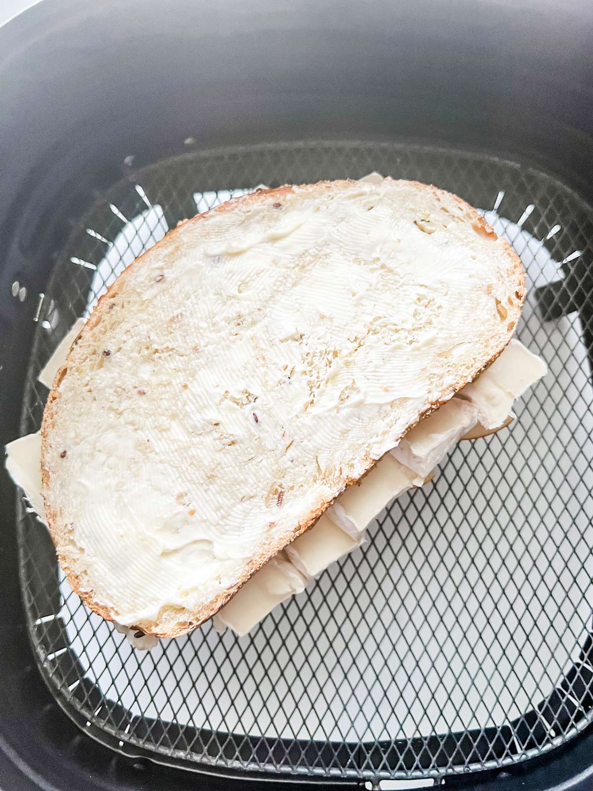 An apple brie sandwich in an air fryer basket.