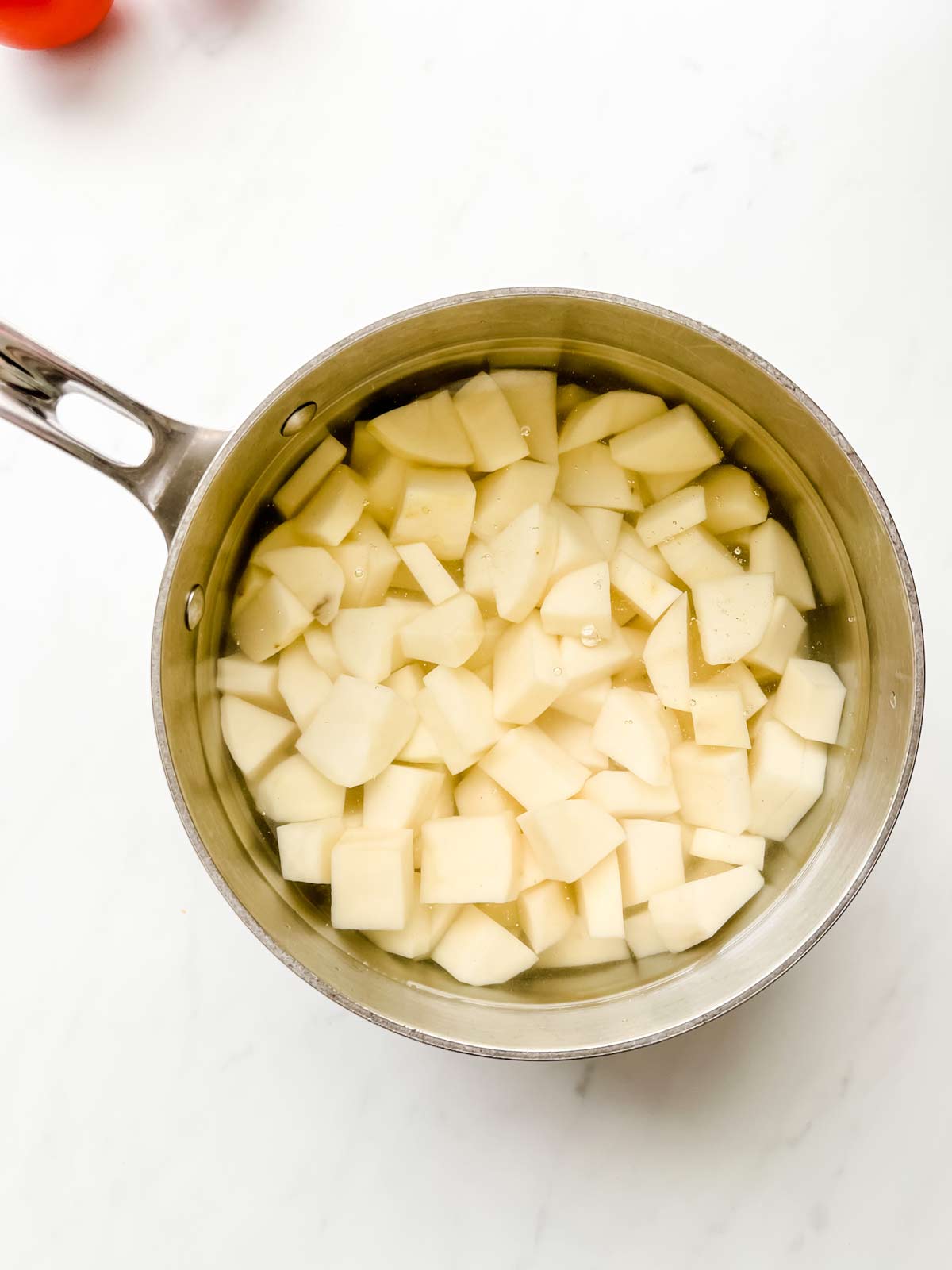 Overhead photo of diced potatoes in a pot of cold water.