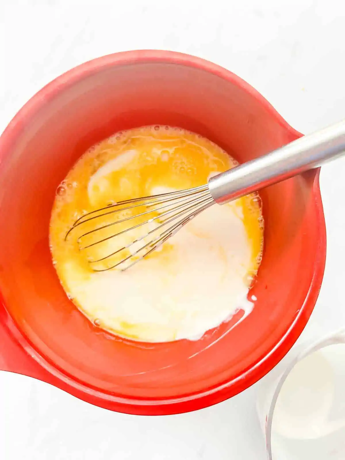 Buttermilk that has been added to egg in a large bowl.