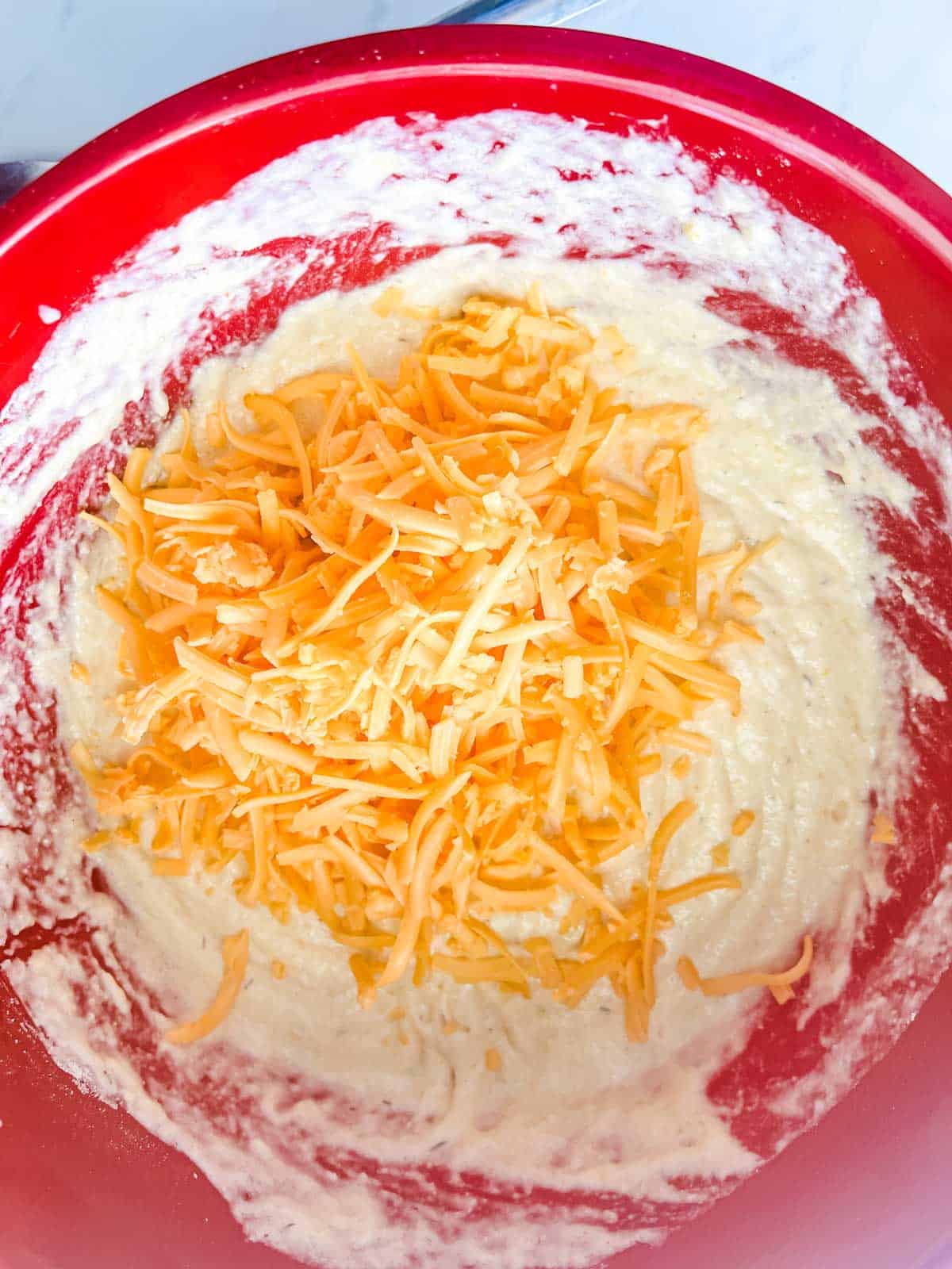 Cornbread batter with cheese added in a large bowl.