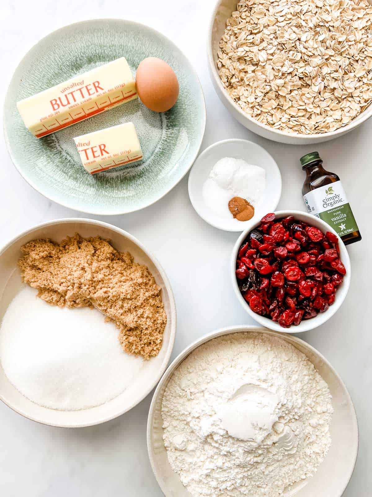 Overhead photo of prepped flour, oats, baking powder, baking soda, cinnamon, butter, eggs, vanilla, and cranberries.