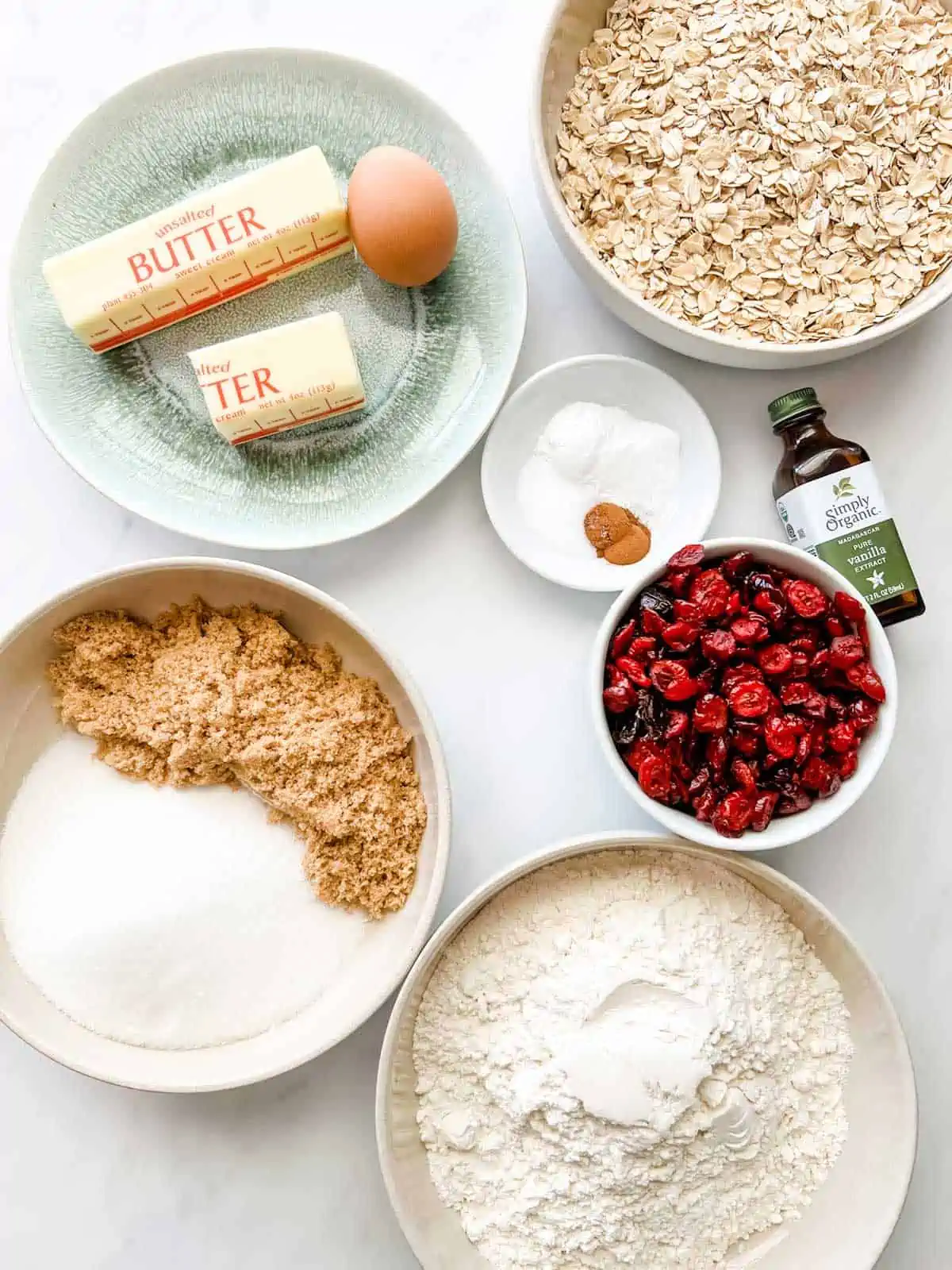 Overhead photo of prepped flour, oats, baking powder, baking soda, cinnamon, butter, eggs, vanilla, and cranberries.