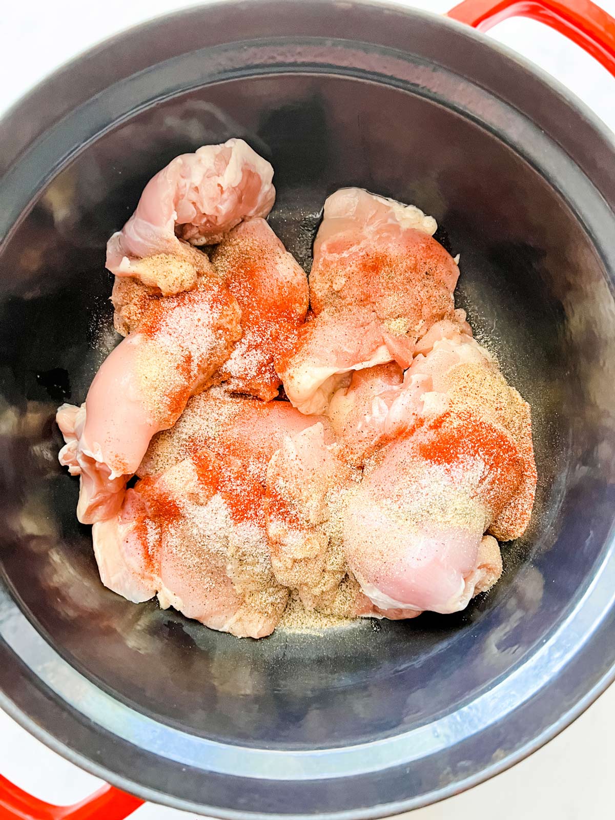 Photo of chicken thighs with seasonings on top.