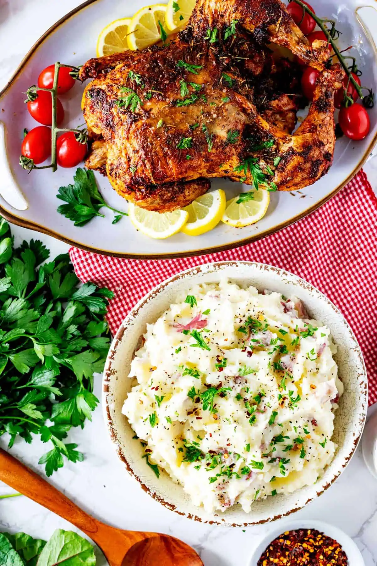 Photo of a bowl of garlic mashed potatoes sitting in front of a roasted chicken.
