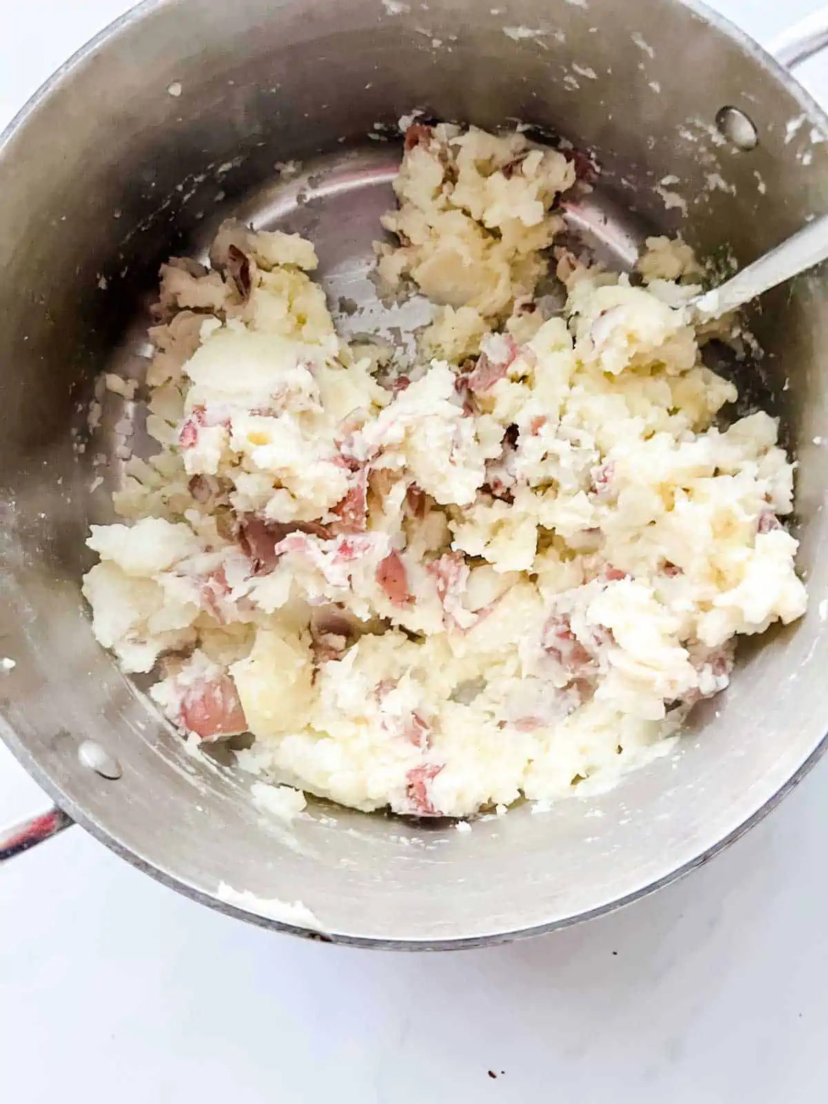Salt, pepper, and butter being incorporated into mashed potatoes.