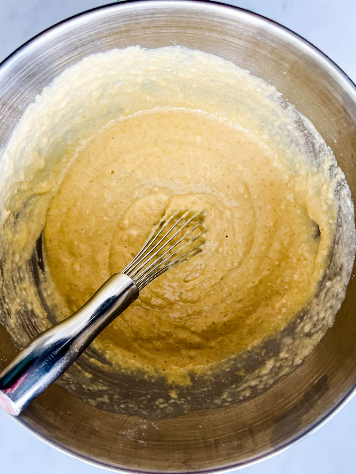 Cornbread mixture being whisked together in a large bowl.