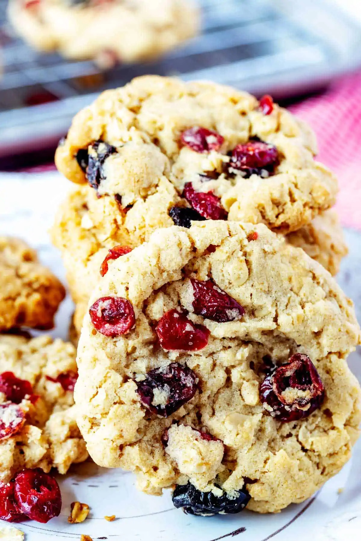 Close up photo of an oatmeal cranberry cookie resting on its side against a stack of cookies.