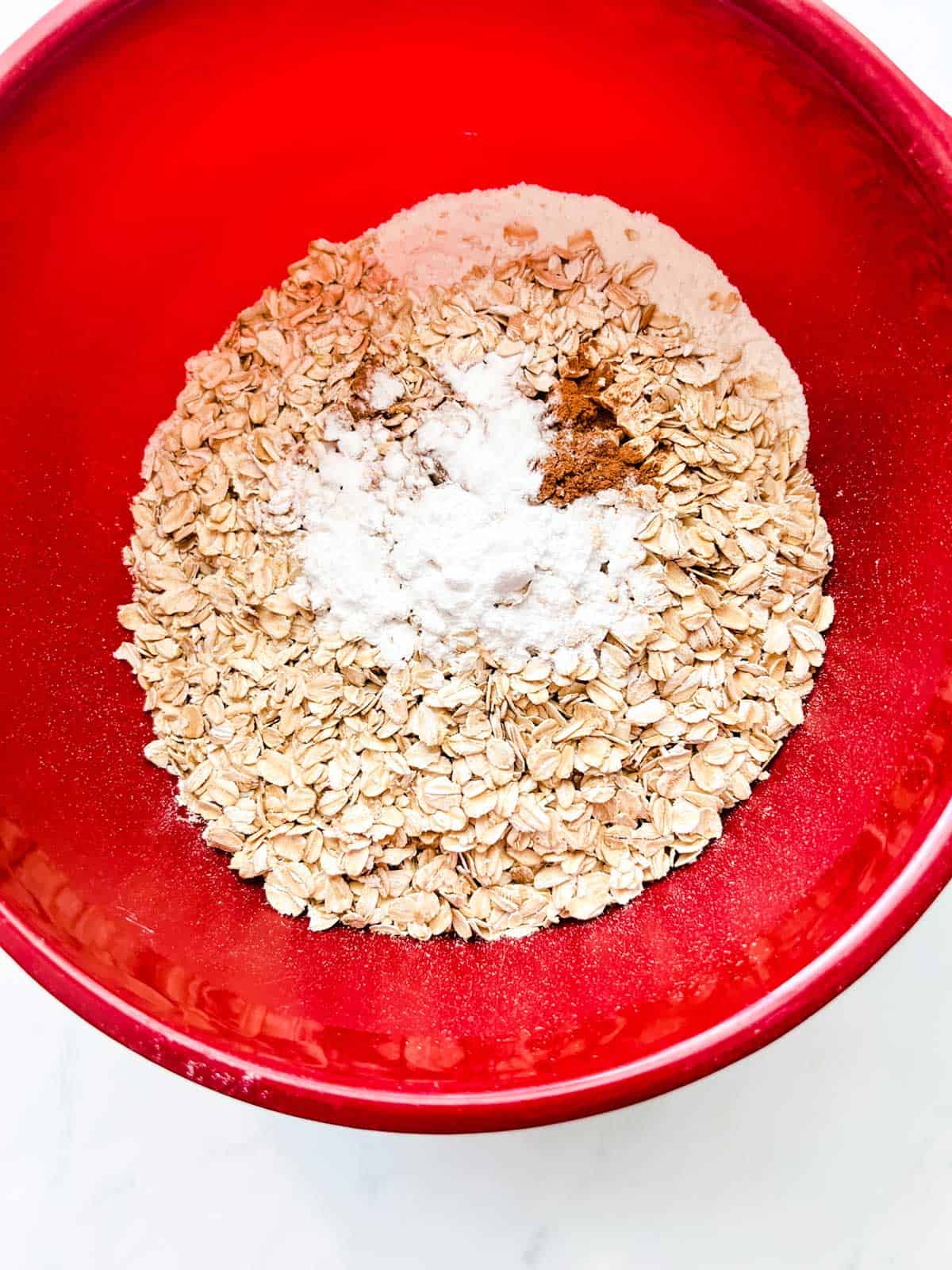 Photo of flour, oats, baking powder, baking soda, cinnamon, and salt in a bowl.