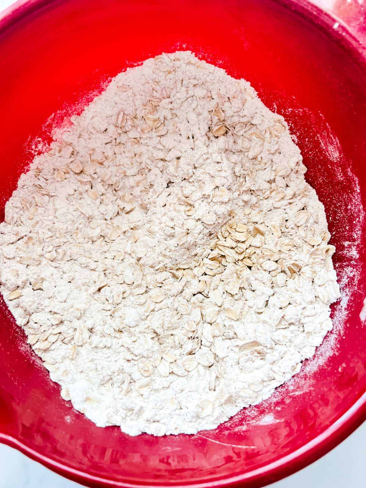 Photo of mixed flour, oats, baking powder, baking soda, cinnamon, and salt in a bowl.