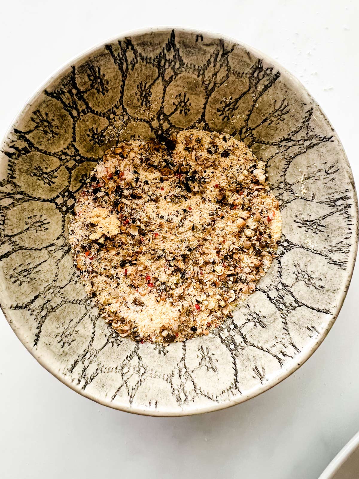 Crushed peppercorns, salt, and garlic powder in a small bowl.