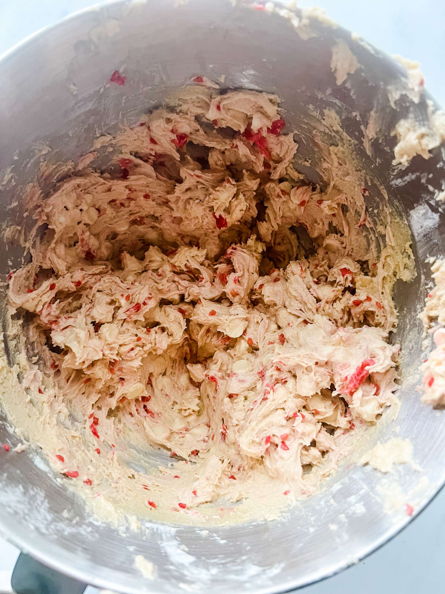 Photo of white chocolate raspberry cookies in the bowl of a stand mixer.