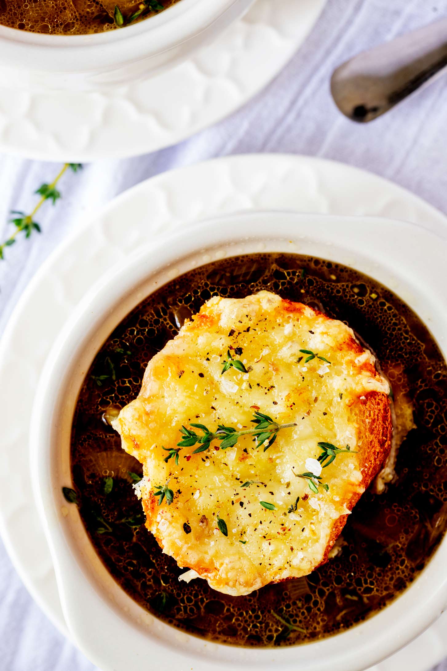 Close up overhead photo of a bowl of Ninja Foodi French Onion soup garnished with thyme.