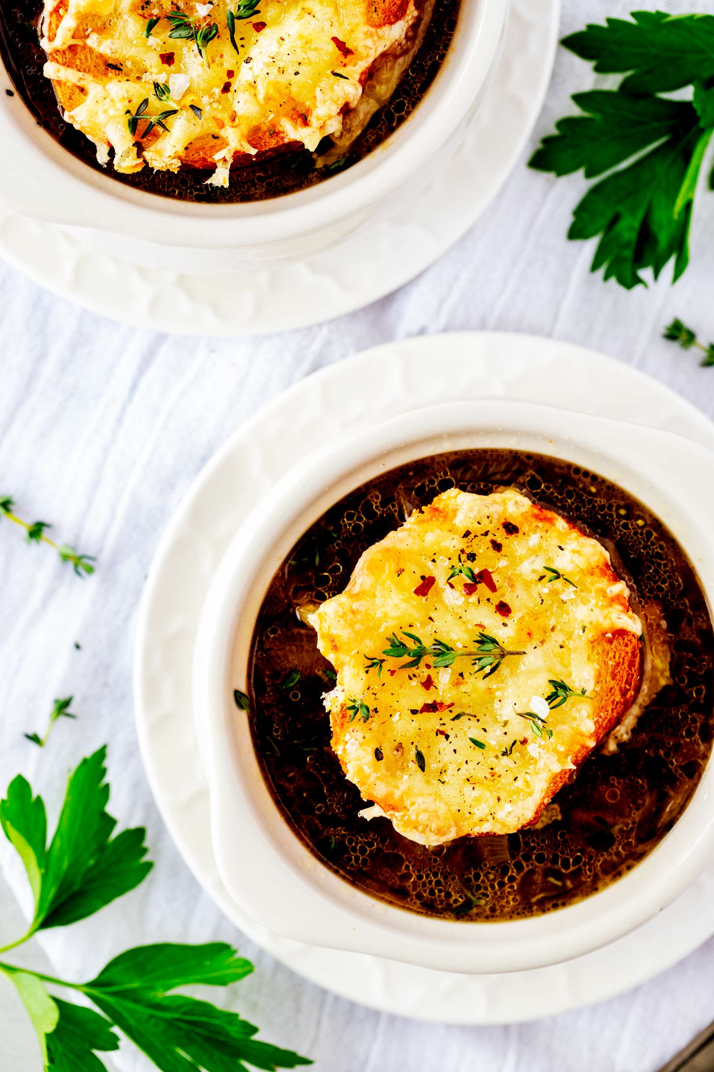 Overhead photo of two soup crocks with Ninja Foodi French Onion Soup set on small white plates.
