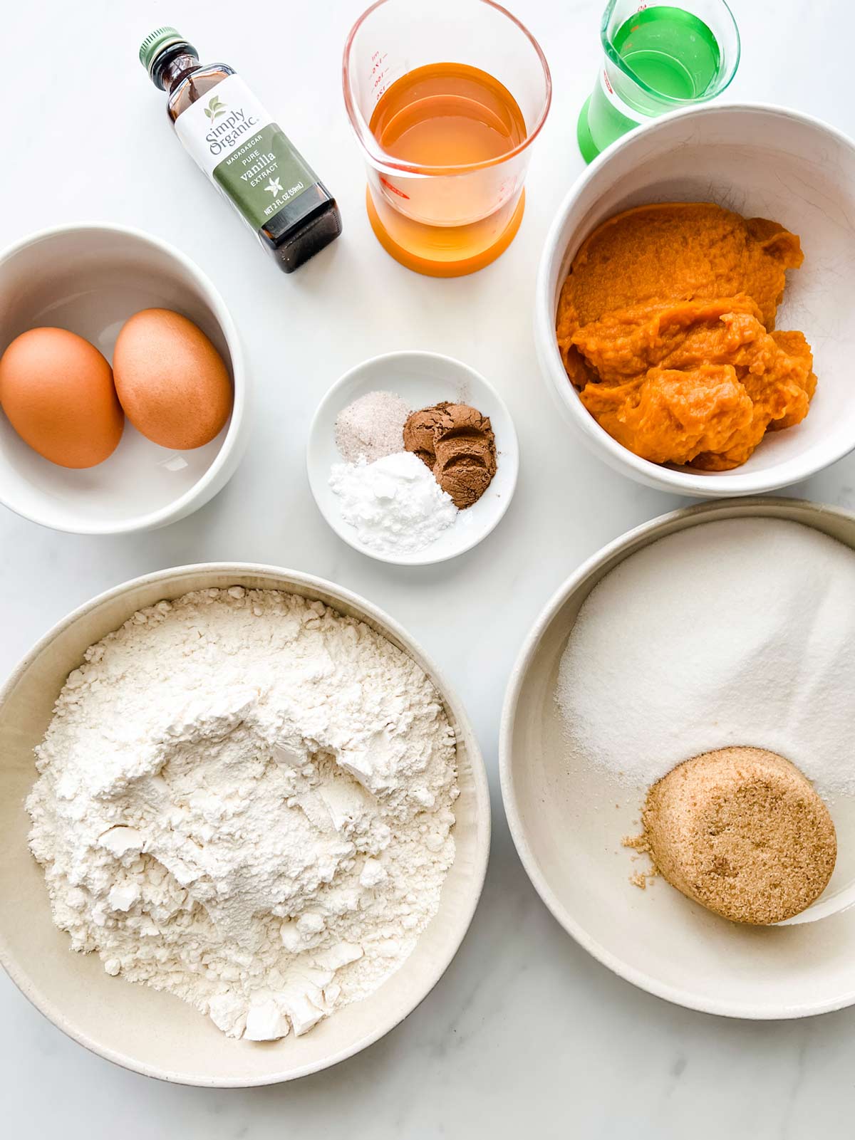 Overhead photo of prep containers with flour, brown sugar, white sugar, pumpkin puree, eggs, baking soda, baking powder, vanilla, and oill