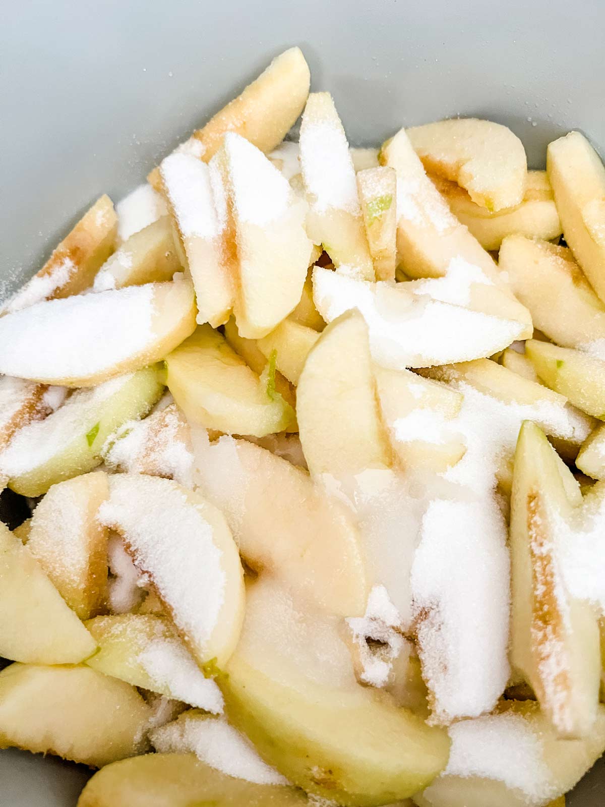Photo of apples that have been coated and lemon juice and sprinkled with sugar being sauteed.