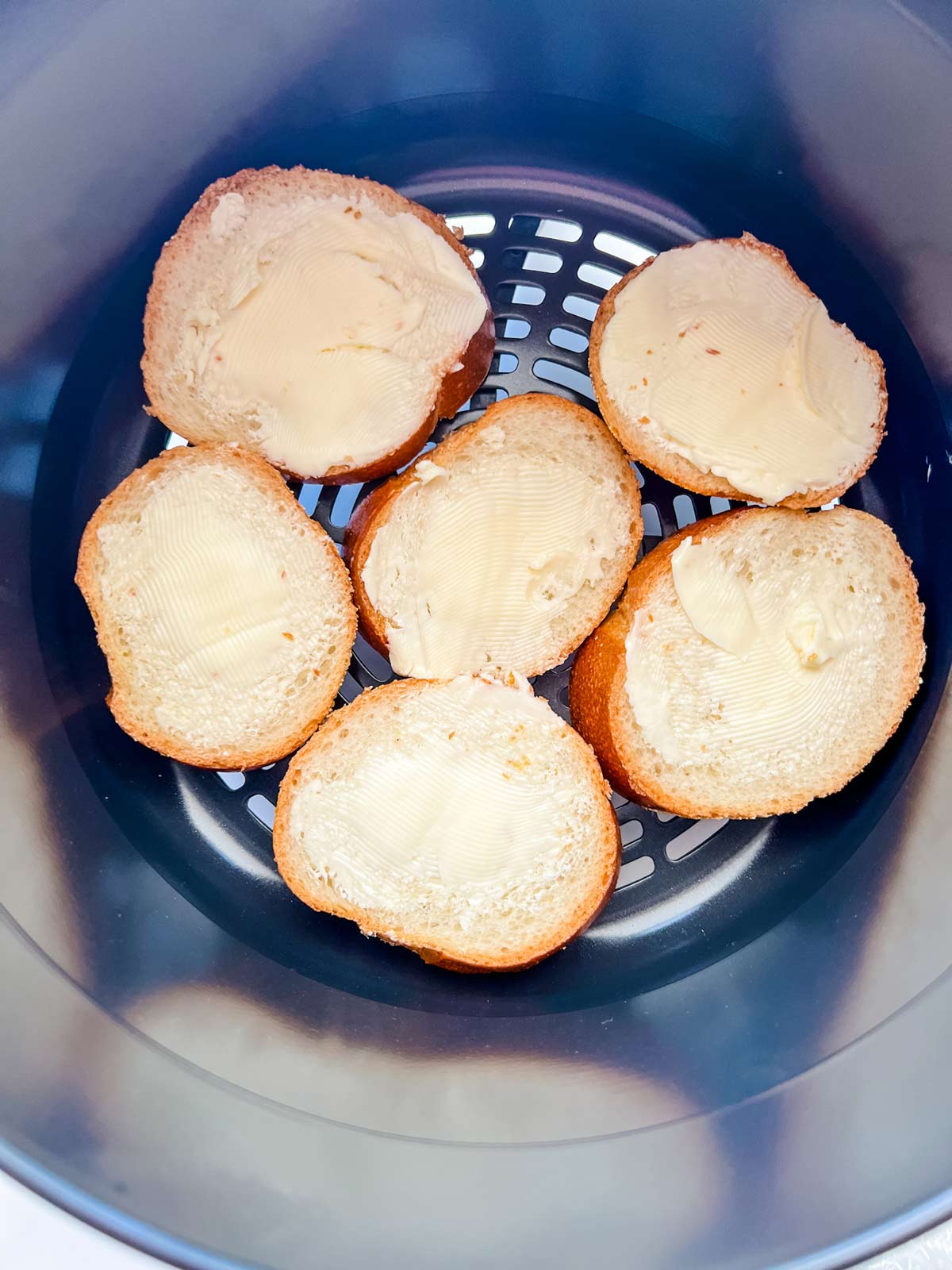 Buttered french bread in the air fryer basket of a Ninja Foodi.