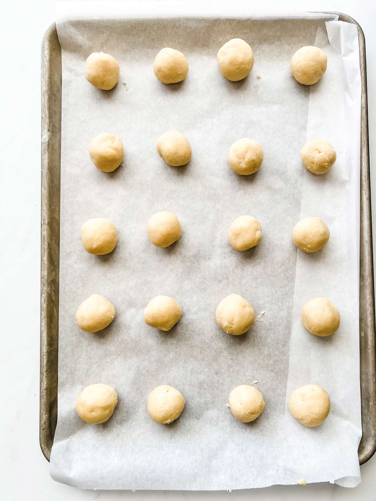 Thumbprint cookie dough rolled out on a parchment lined baking sheet.