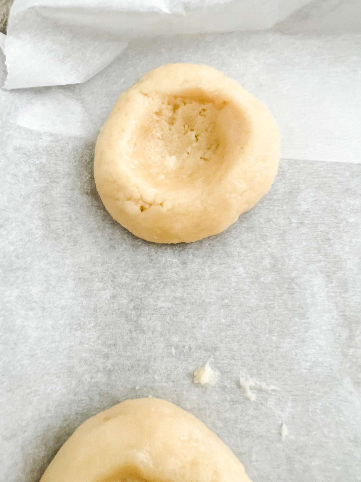 Thumbprint cookie that is unfilled and ready to bake.