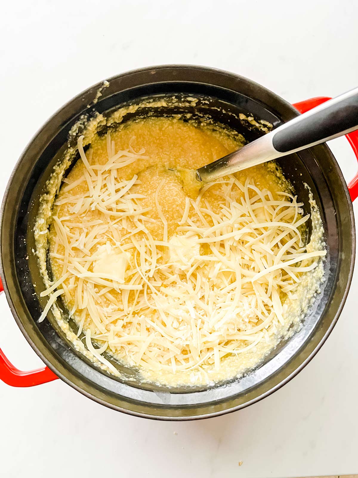 Cooked slow cooker polenta with parmesan and butter on top.