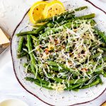 Square photo of Ninja Foodi green beans topped with parmesan and garnished with crushed red pepper flakes.