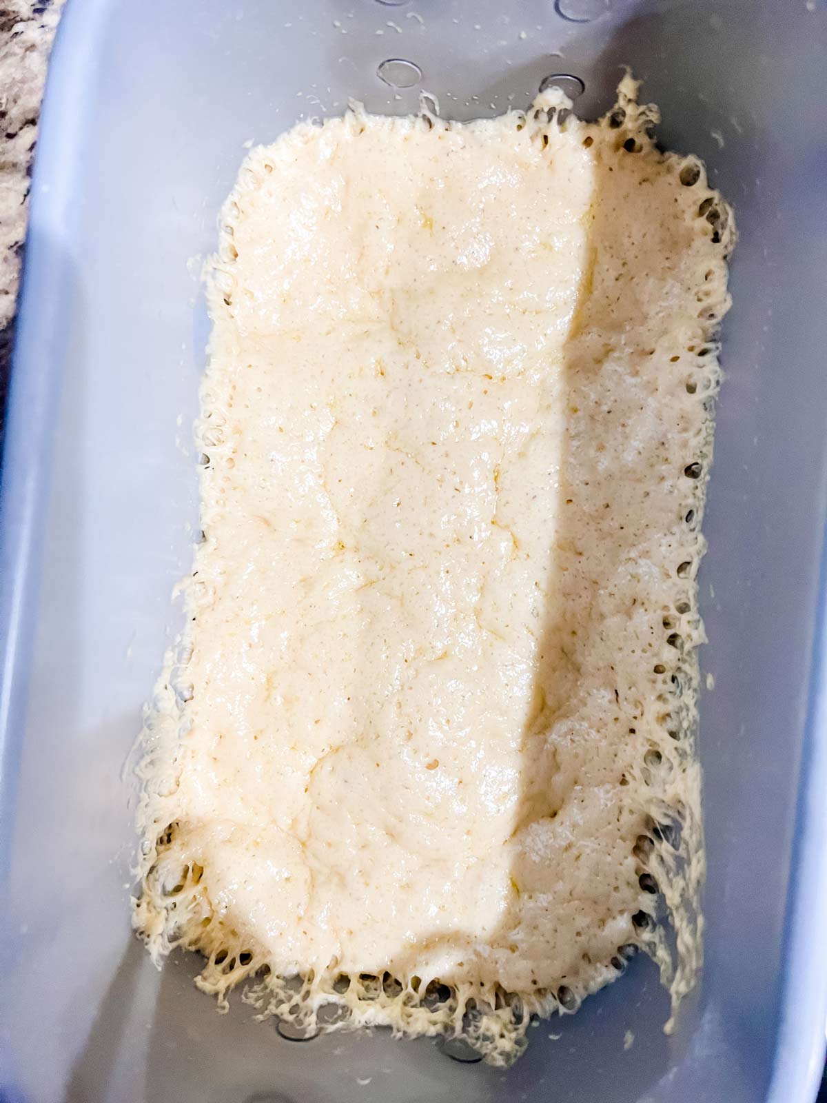 Brioche dough in the pan of a bread machine.
