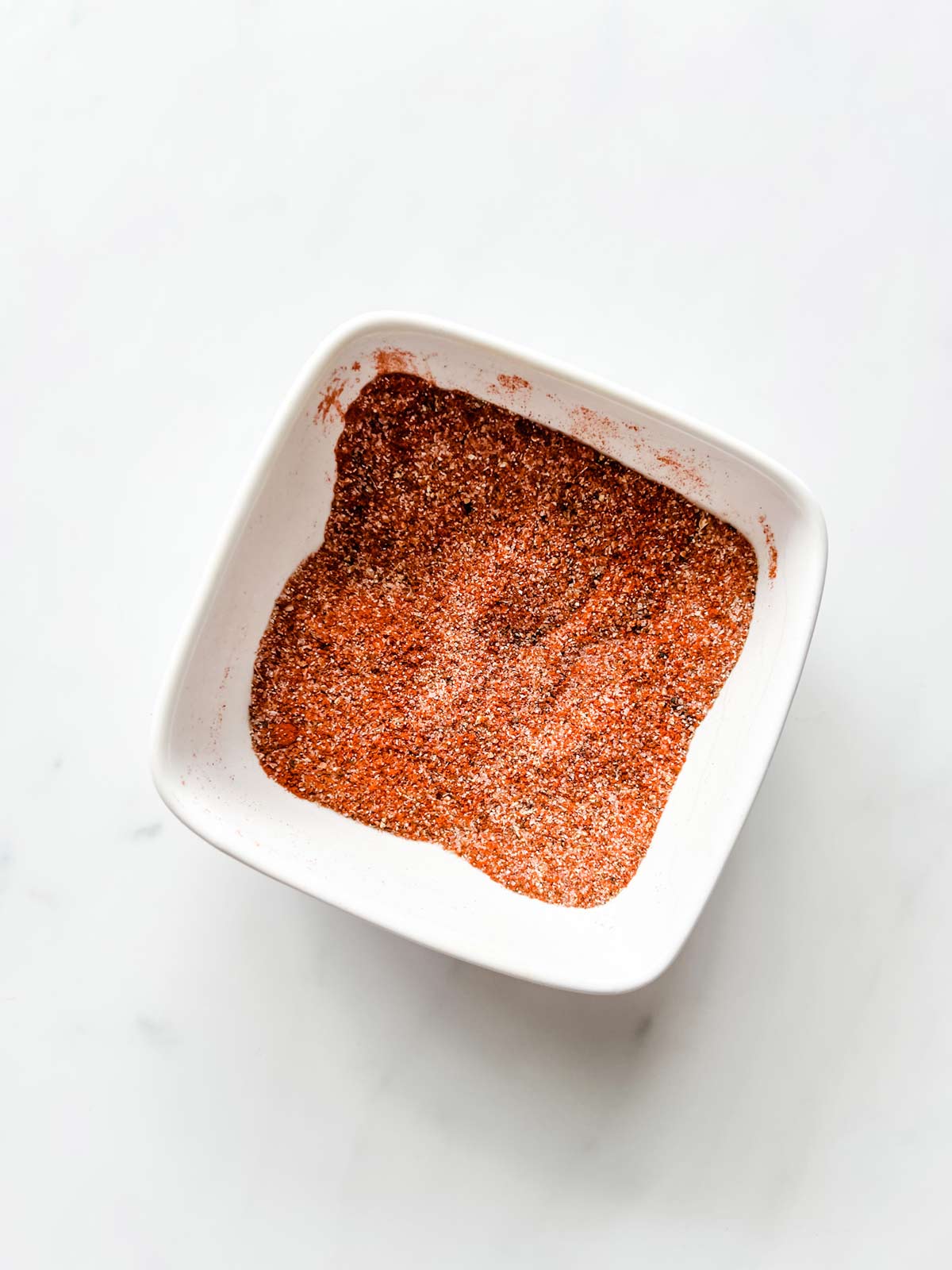 Small square white bowl with a seasoning mixture in it.