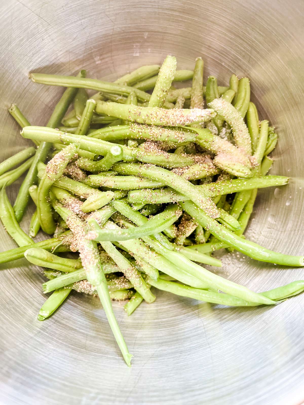 Photo of green beans in a bowl with salt and pepper.