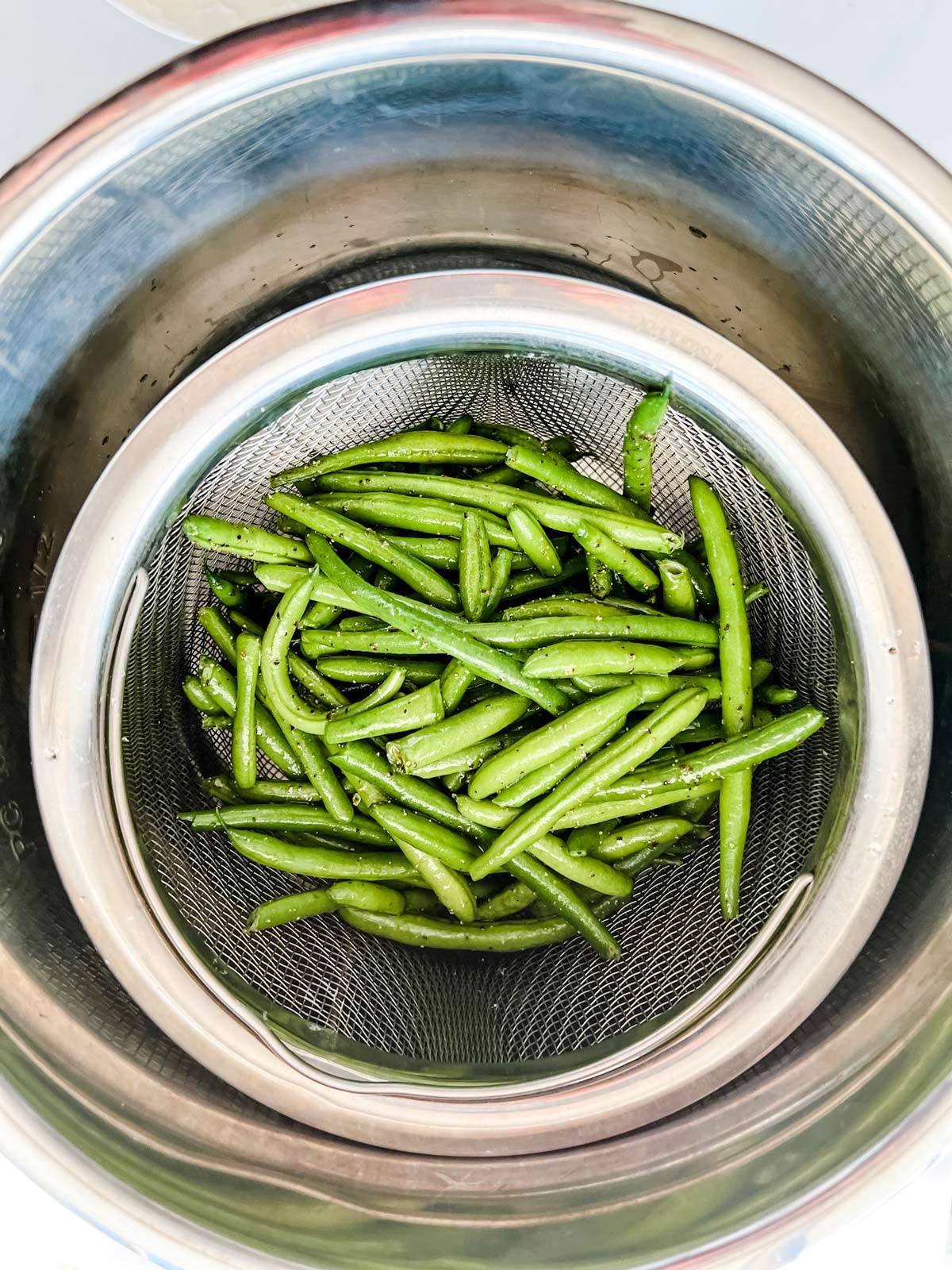 Photo of green beans in a steamer basket set inside the inner pot of an Instant Pot.