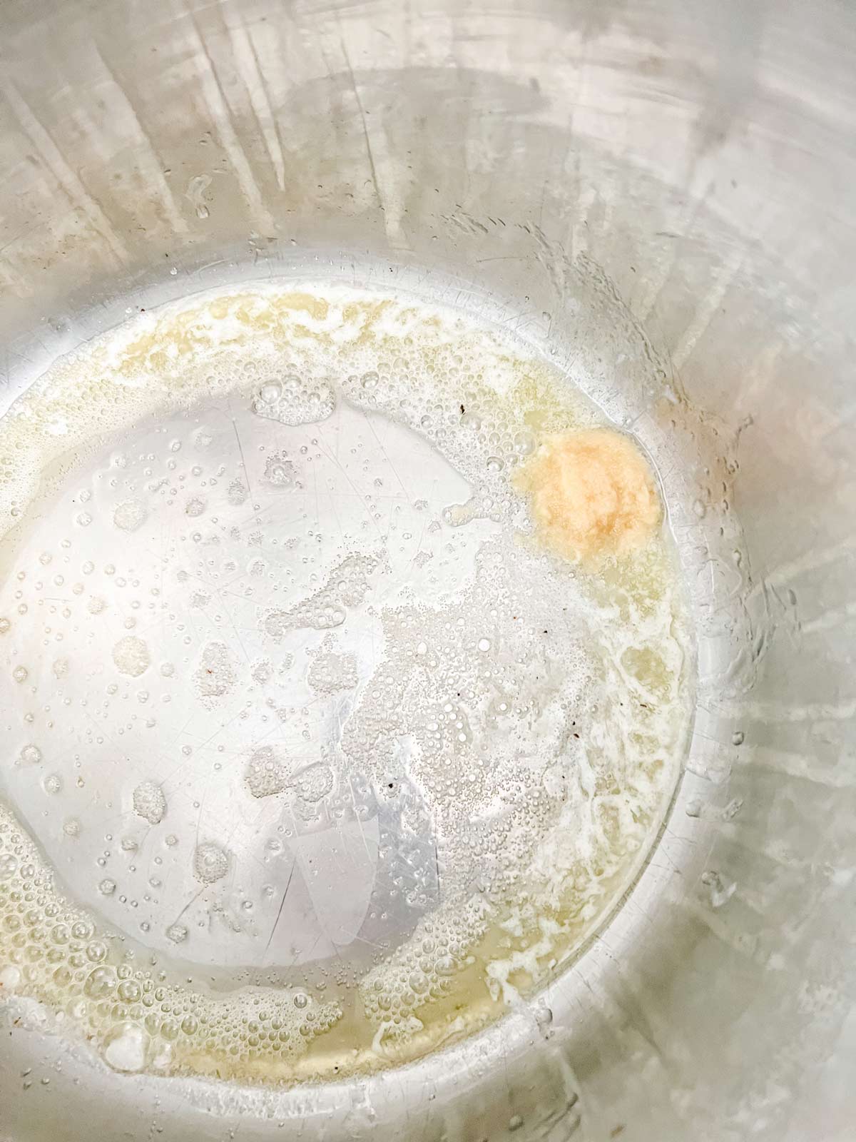 Photo of garlic sautéing in the inner pot of an Instant Pot. 