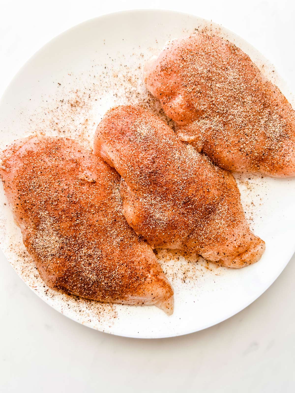 Seasoned chicken breast on a plate.