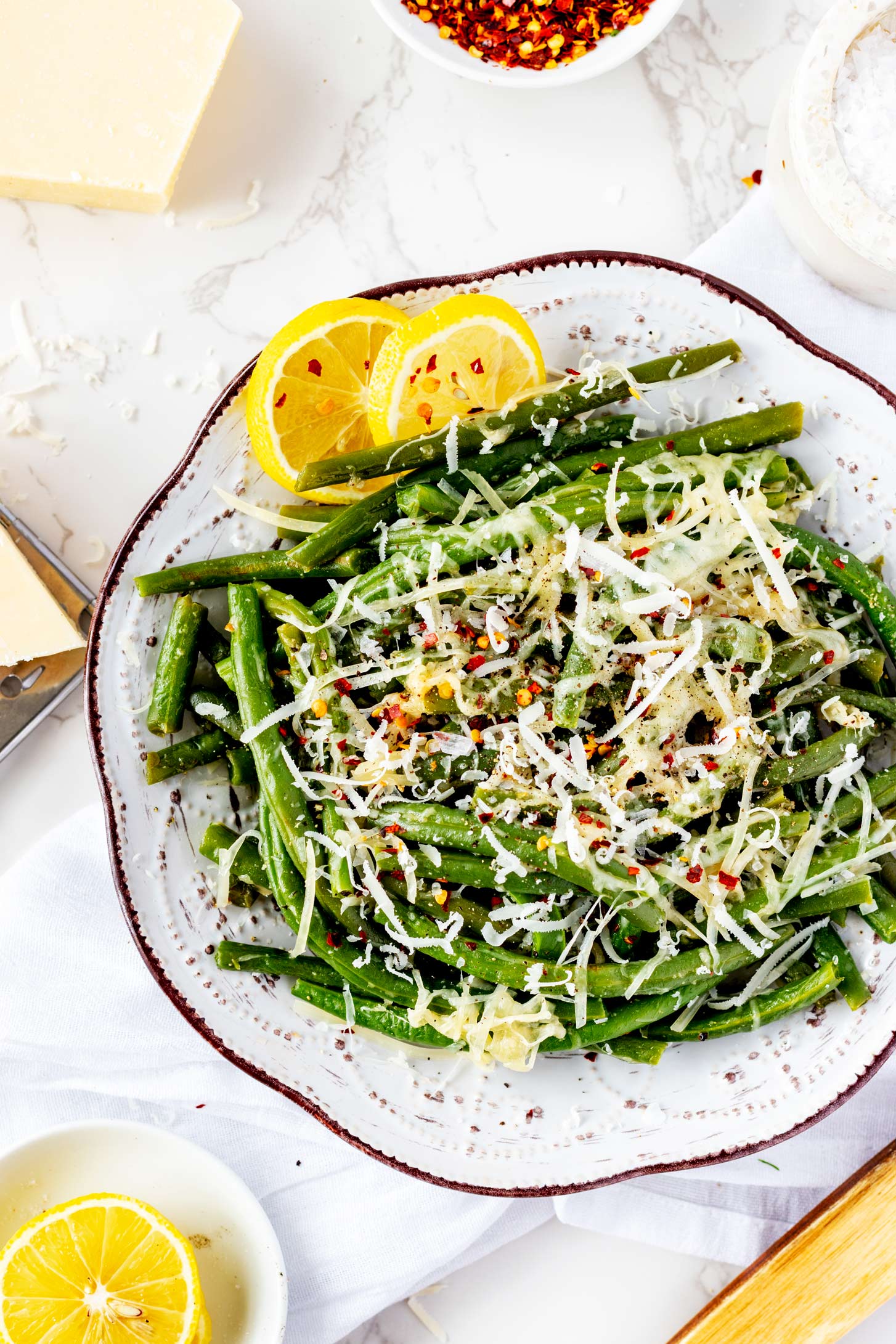 Overhead photo of a rustic plate with Ninja Foodi green beans garnished with crushed red pepper flakes.