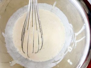 A milk and egg mixture combined with heavy cream in a bowl.