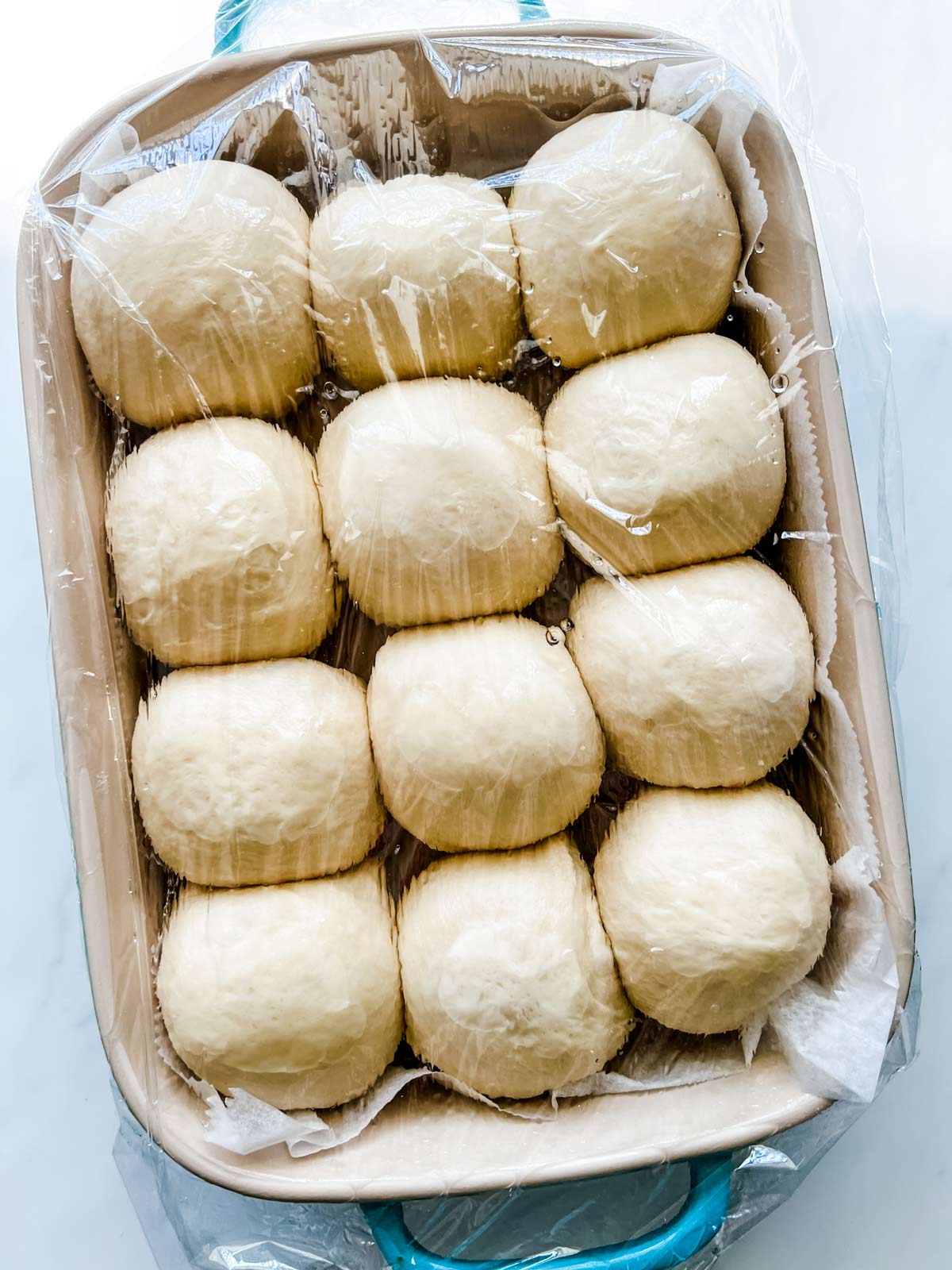 Dinner rolls that have risen covered in plastic wrap.