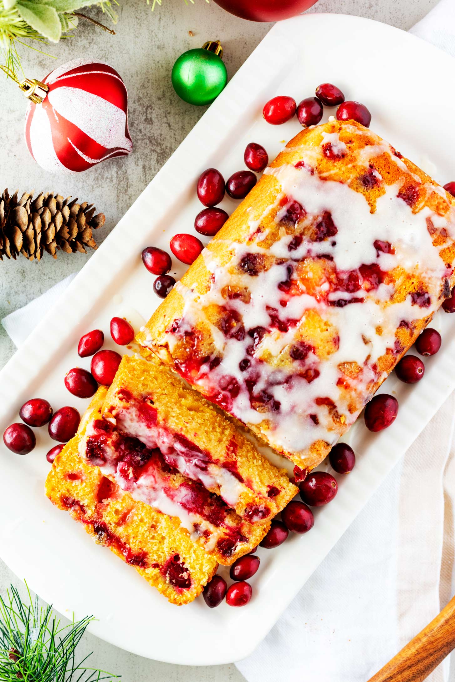 Overhead photo of a loaf of cranberry orange bread on a white platter.