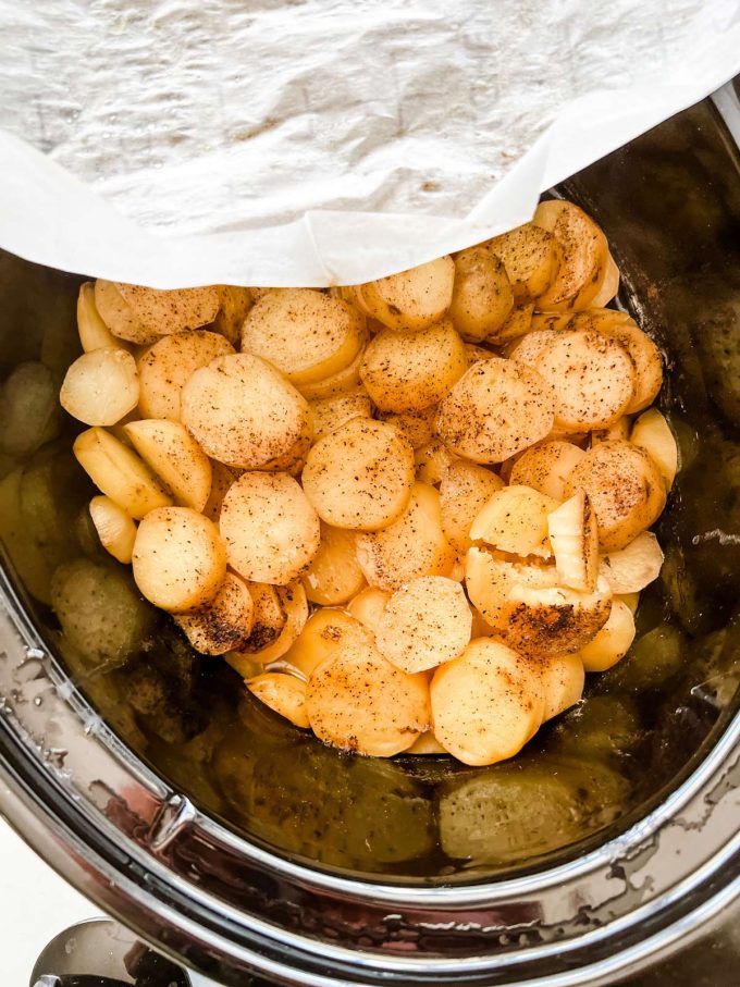 Photo of cooked potato slices in a crockpot having the parchment paper removed.