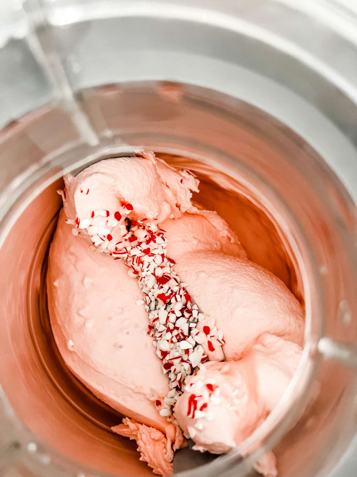 Peppermint ice cream that has started to firm up in the bowl of an ice cream maker.