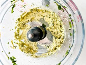 Photo of butter, seasonings, herbs, and lemon zest that have been blended in a food processor.