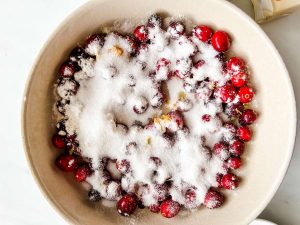 Cranberries, sugar, orange zest, lemon zest, and flour in a bowl.