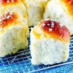 Photo of bread machine dinner rolls on a cooling rack.