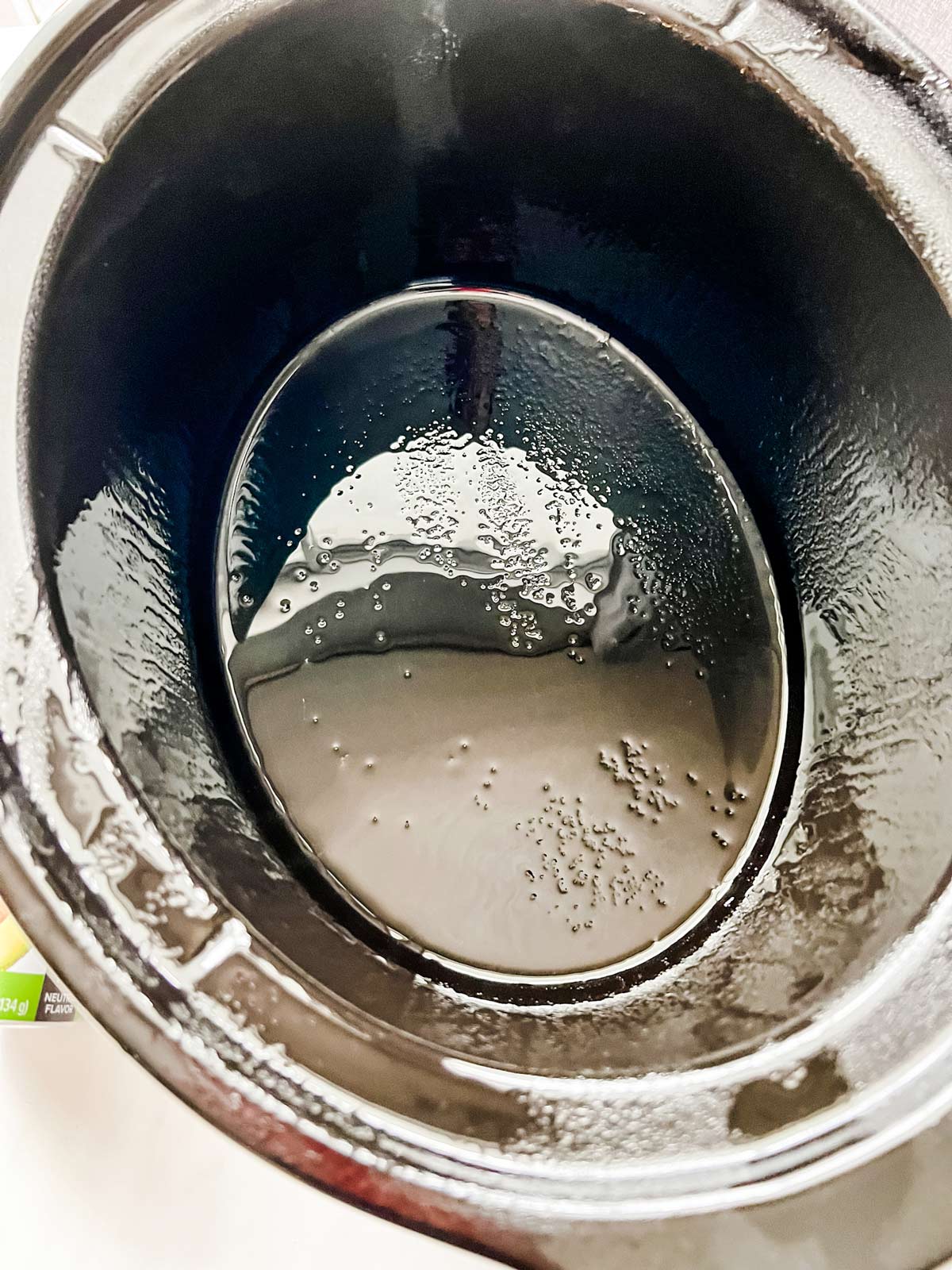 A slow cooker sprayed with cooking spray.