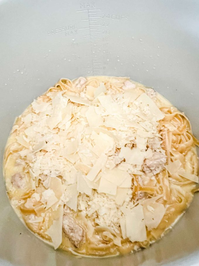 Cheese on top of chicken alfredo in the bowl of a Ninja Foodi.