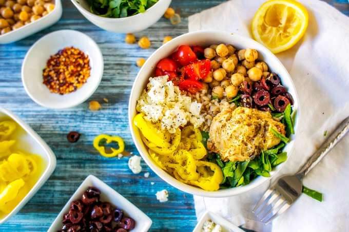 Horizontal photo of a mediteranean bowl surrounded by bowls of ingredients.