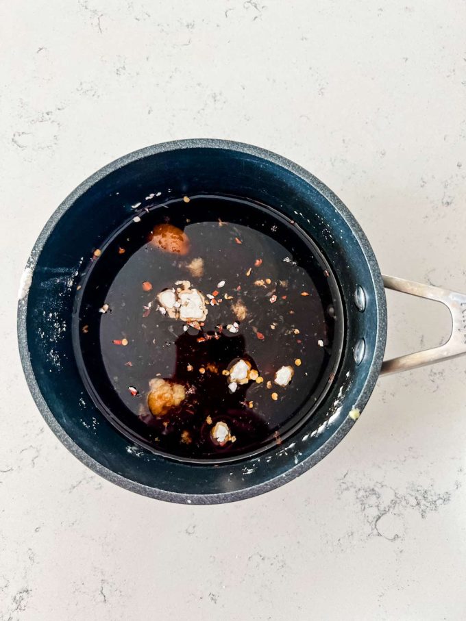 Overhead photo of mirin, soy sauce, sugar, cornstarch, ginger, and red pepper flakes in a small saucepan.
