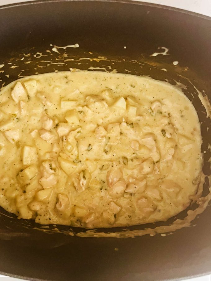 Creamy chicken, potatoes, and onion in a slow cooker.