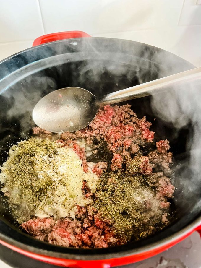 Ground beef, onion, and seasonings cooking using the saute function of a slow cooker.